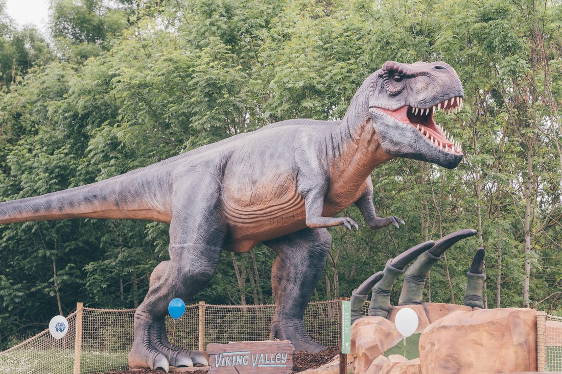 The Tyrannosaurus Rex rearing over its green, with giant claws bursting from the ground